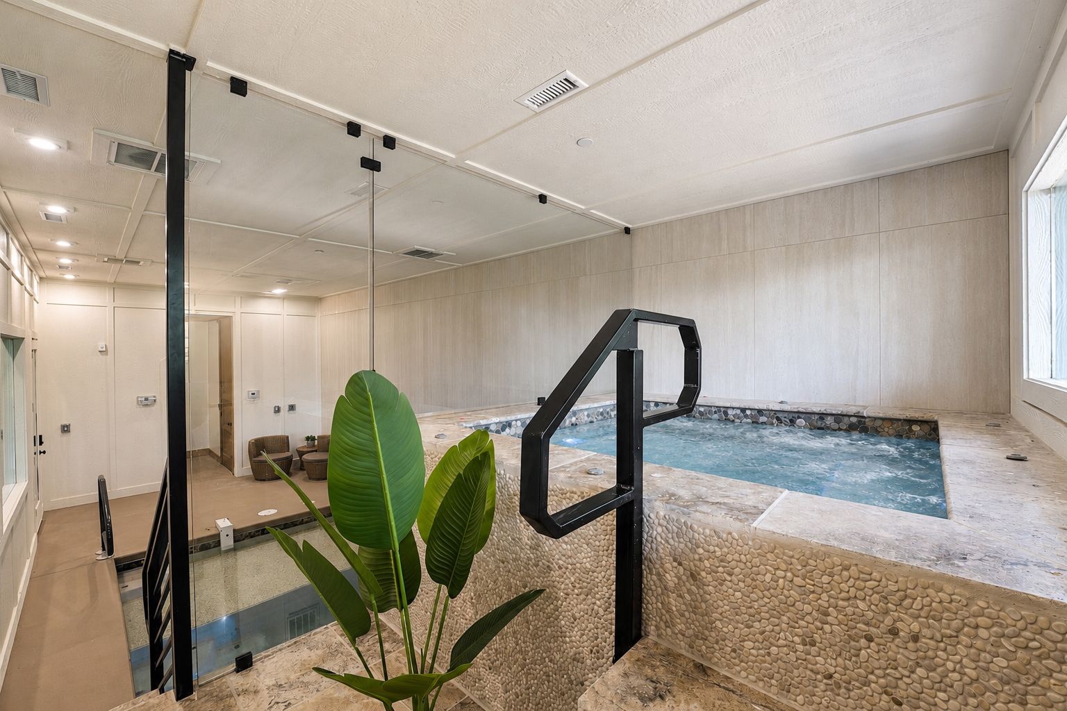 Indoor spa and pool room with pebble-tile surround